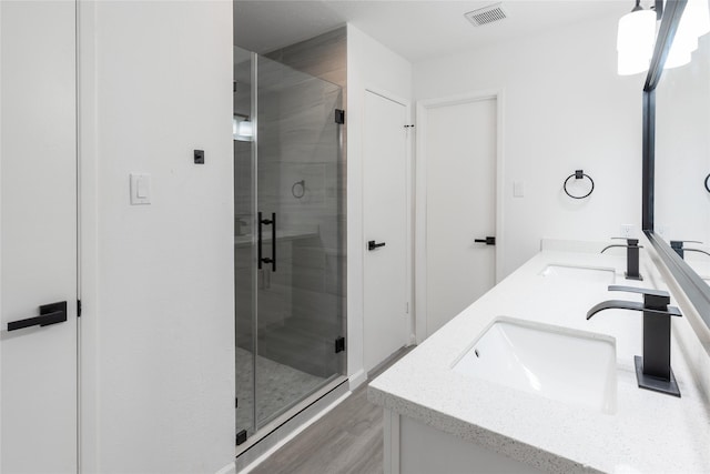 bathroom featuring double vanity, a stall shower, a sink, and visible vents