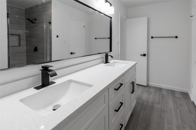 full bath featuring a stall shower, wood finished floors, a sink, and double vanity