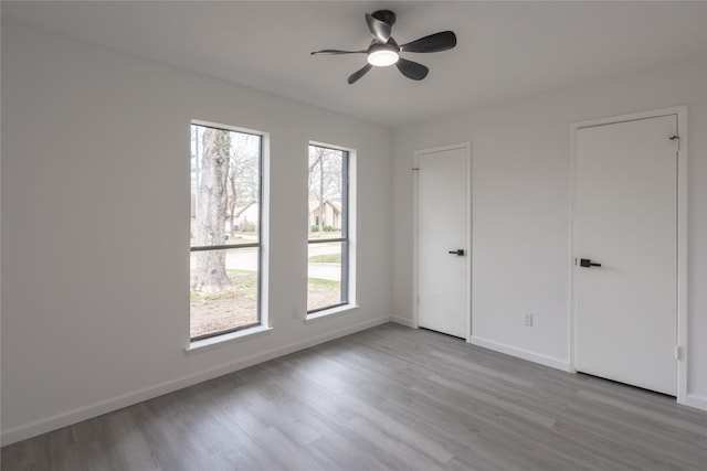 unfurnished bedroom with multiple windows, baseboards, and wood finished floors