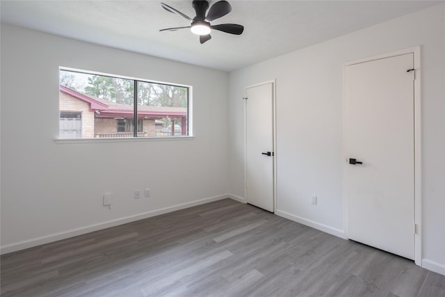 empty room featuring ceiling fan, wood finished floors, and baseboards