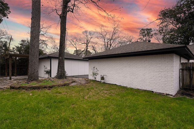 view of home's exterior featuring fence, an outdoor structure, a lawn, and brick siding