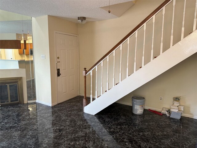 2120 El Paseo St Unit 3301, Houston, TX 77054 - foyer entrance featuring marble look tiles, stairway, a textured ceiling, and a glass covered fireplace