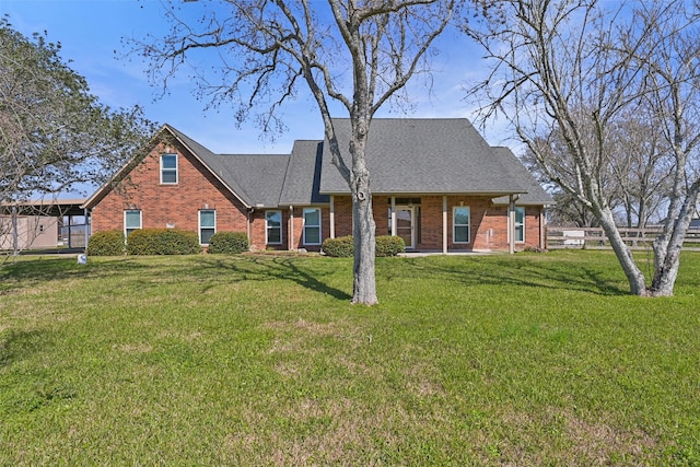 view of front of house with roof with shingles, brick siding, and a front lawn