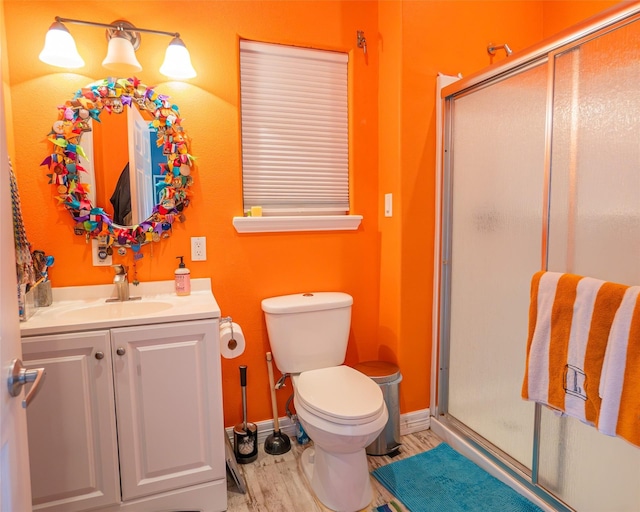 bathroom featuring a stall shower, baseboards, toilet, wood finished floors, and vanity