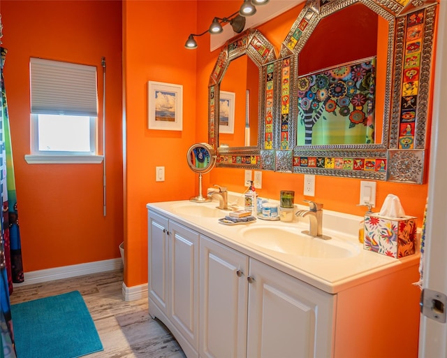 full bathroom featuring double vanity, a sink, baseboards, and wood finished floors