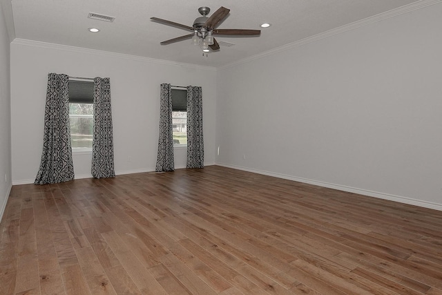 empty room featuring ceiling fan, visible vents, wood finished floors, and crown molding