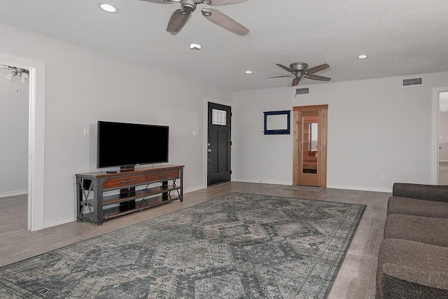 living room with recessed lighting, visible vents, and a textured ceiling