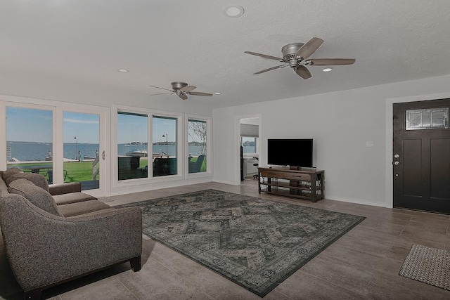 living area featuring ceiling fan, plenty of natural light, a textured ceiling, and wood finished floors