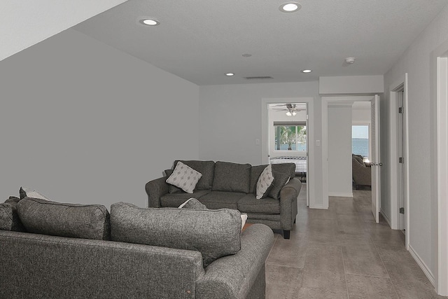 living room featuring visible vents, recessed lighting, a textured ceiling, and baseboards