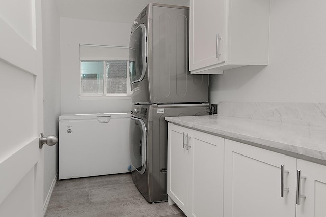 washroom with cabinet space and stacked washer and clothes dryer