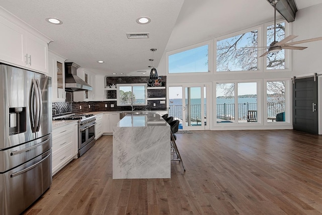 kitchen with visible vents, dark wood-style floors, stainless steel appliances, wall chimney exhaust hood, and open shelves