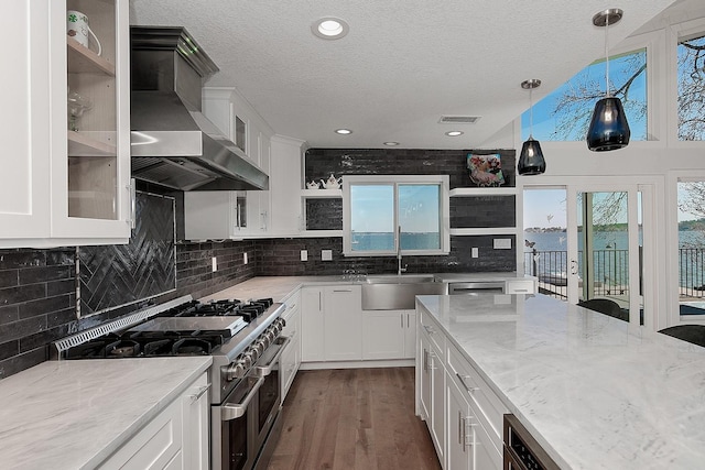 kitchen with visible vents, open shelves, a sink, appliances with stainless steel finishes, and wall chimney range hood