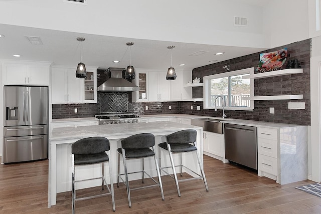 kitchen with visible vents, open shelves, a sink, appliances with stainless steel finishes, and wall chimney range hood