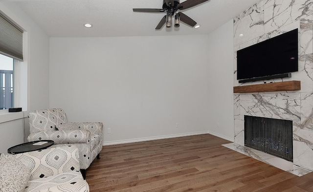 unfurnished room with a ceiling fan, wood finished floors, recessed lighting, a premium fireplace, and baseboards