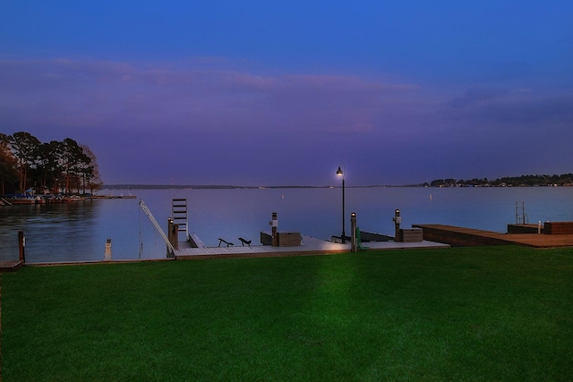 view of dock with a yard and a water view