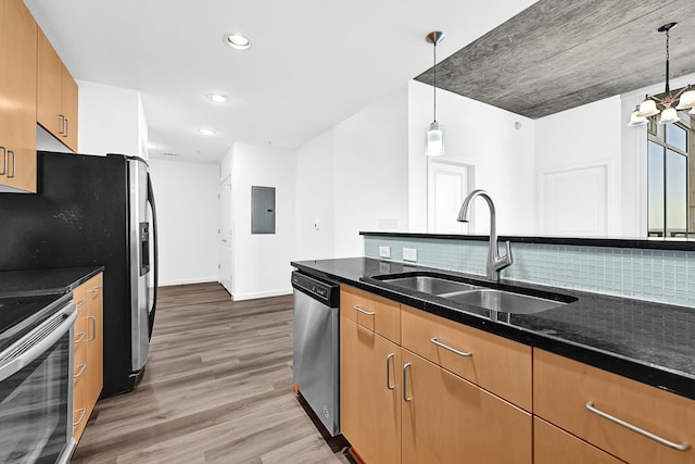 kitchen featuring appliances with stainless steel finishes, pendant lighting, a sink, and wood finished floors