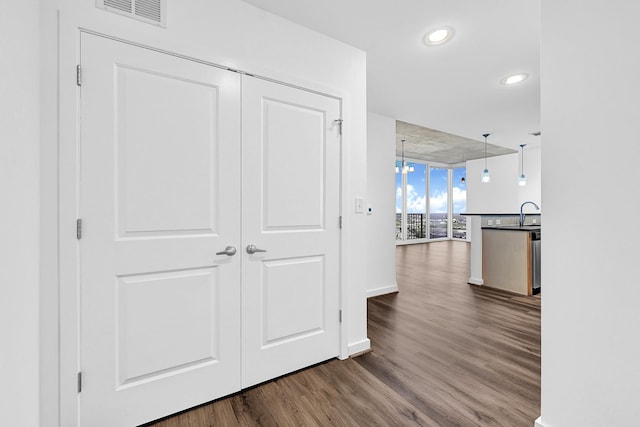 hall featuring baseboards, visible vents, dark wood finished floors, floor to ceiling windows, and recessed lighting