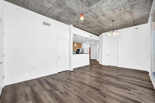 unfurnished living room featuring a chandelier, dark wood-type flooring, visible vents, and baseboards