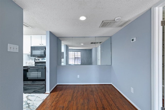 spare room featuring a textured ceiling, visible vents, and baseboards