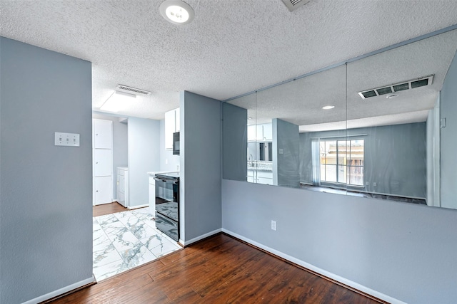 unfurnished room with baseboards, visible vents, and wood finished floors