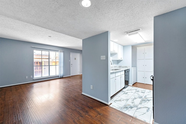 kitchen with baseboards, visible vents, wood finished floors, white cabinetry, and a sink