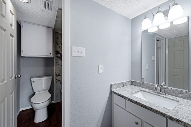 bathroom featuring toilet, a textured ceiling, vanity, and wood finished floors
