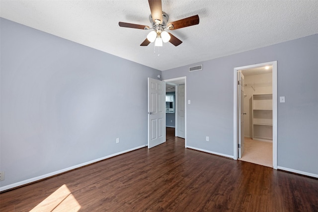unfurnished bedroom with baseboards, a textured ceiling, visible vents, and dark wood-type flooring