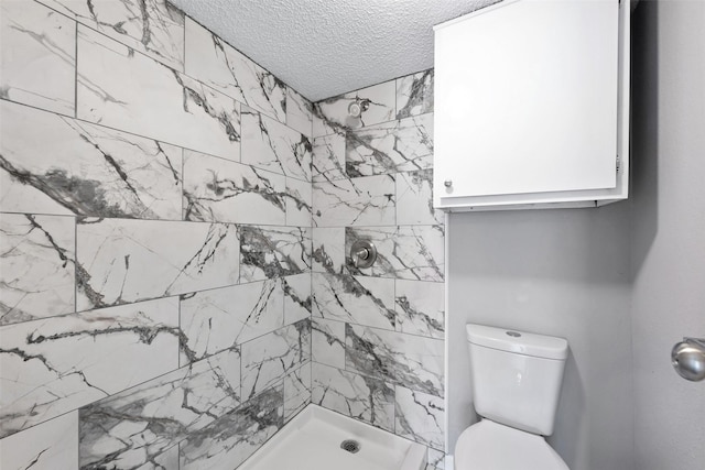 full bath with a textured ceiling, tiled shower, and toilet