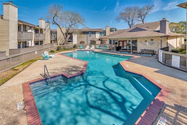 community pool with a residential view, a patio area, and fence