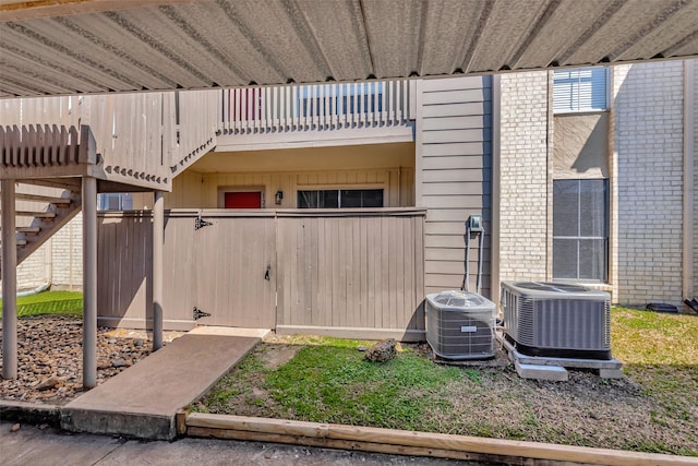 exterior space with central air condition unit, a balcony, a fenced front yard, and brick siding
