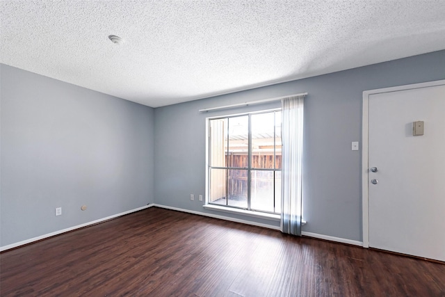 unfurnished room featuring a textured ceiling, wood finished floors, and baseboards