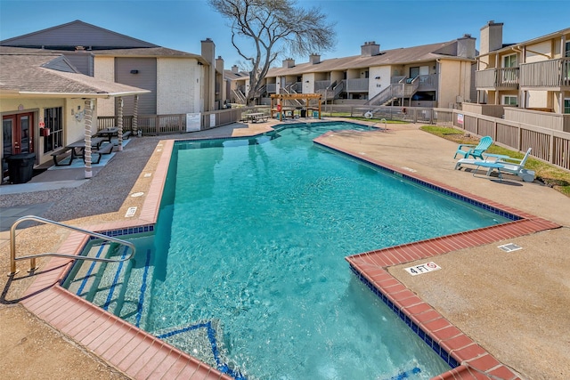 community pool with a patio area, a residential view, fence, and french doors