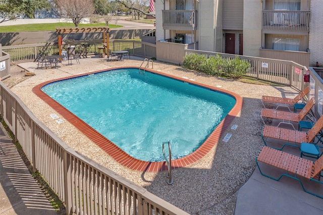 pool with a patio area and fence