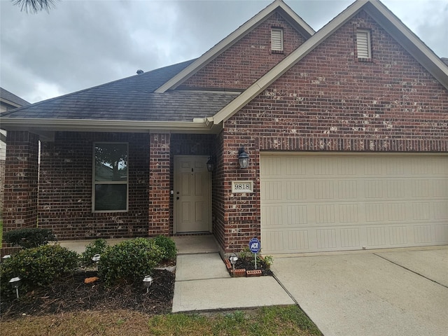 view of front facade featuring a garage, roof with shingles, brick siding, and driveway