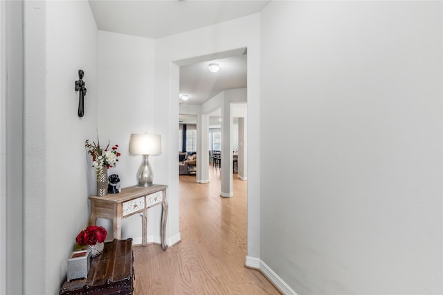 corridor with light wood-style floors and baseboards