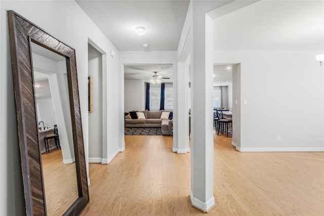 corridor with light wood-style floors and baseboards