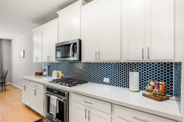 kitchen with stainless steel appliances, white cabinets, light countertops, and decorative backsplash