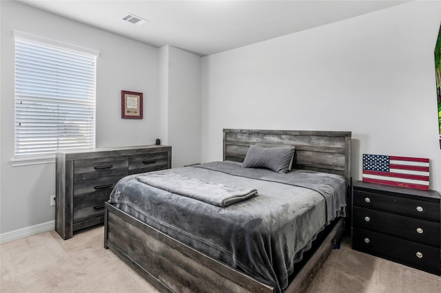 bedroom with visible vents, light carpet, and baseboards