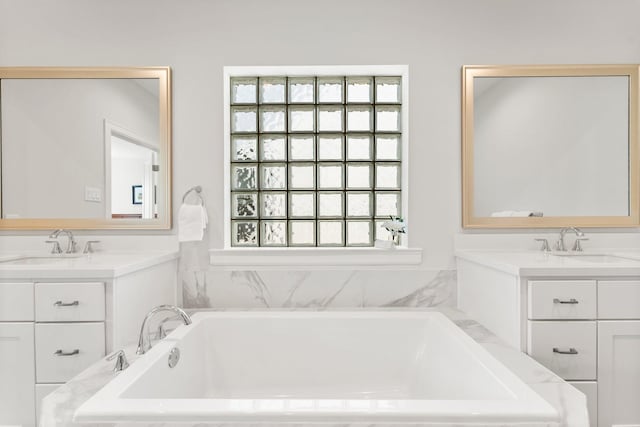 full bath with two vanities, a sink, and a bath