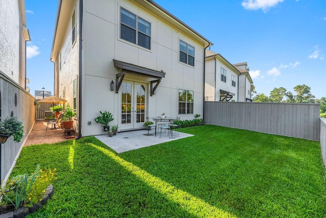 back of property featuring a lawn, a fenced backyard, french doors, a patio area, and stucco siding