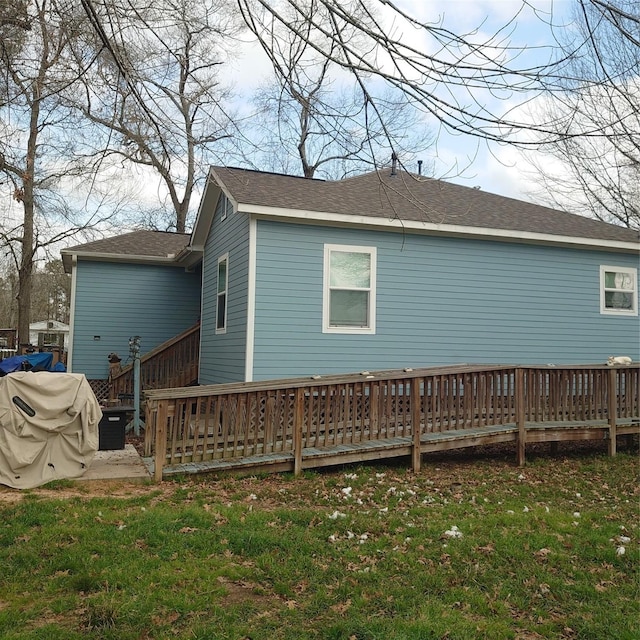 back of property with a deck and a lawn