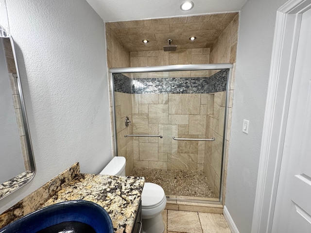 full bathroom with toilet, a stall shower, a textured wall, and vanity