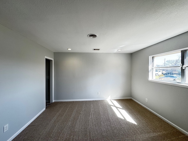 carpeted spare room featuring baseboards, visible vents, and a textured ceiling