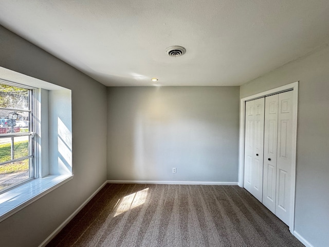 unfurnished bedroom featuring carpet floors, a closet, visible vents, and baseboards