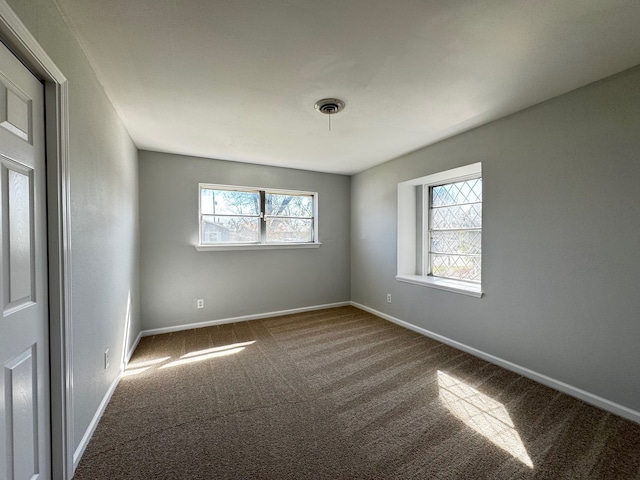 empty room featuring carpet, visible vents, and baseboards