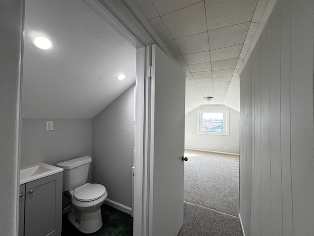 bathroom featuring lofted ceiling, baseboards, toilet, and vanity