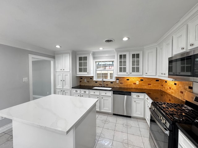 kitchen featuring visible vents, decorative backsplash, appliances with stainless steel finishes, white cabinetry, and a sink