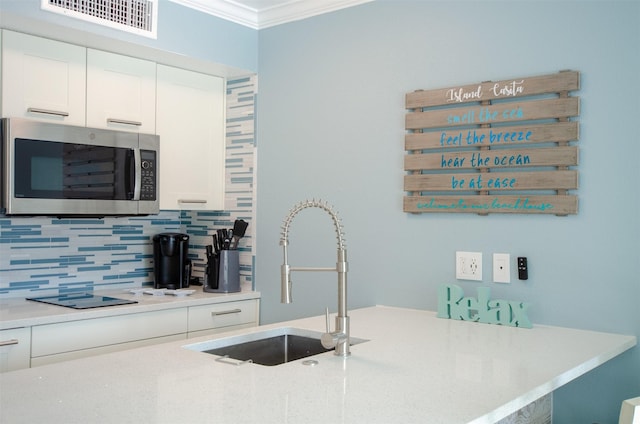 6300 Seawall Blvd Unit 9108, Galveston, TX 77551 - kitchen featuring crown molding, a sink, tasteful backsplash, stainless steel microwave, and visible vents