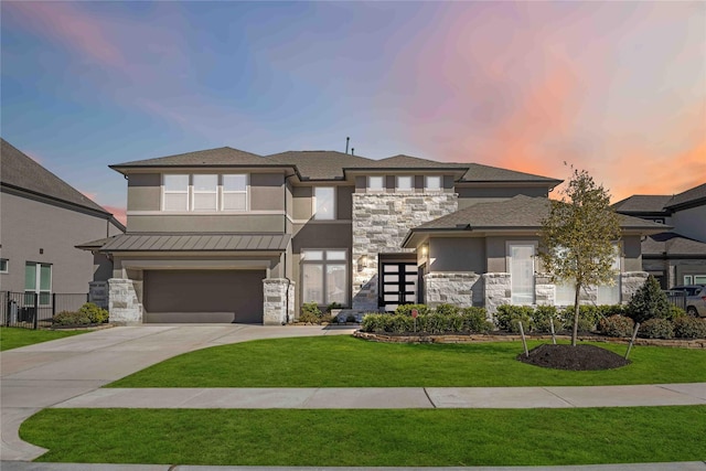 prairie-style house featuring stone siding, a lawn, concrete driveway, and an attached garage