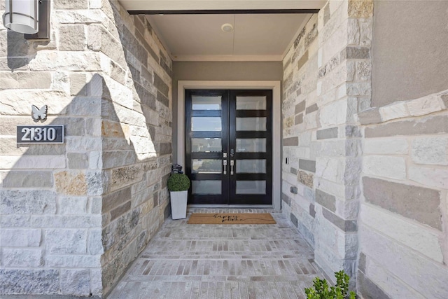 entrance to property featuring stone siding and french doors